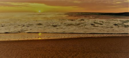 Ocean waves coming into the sandy shore of the beach at sunrise.