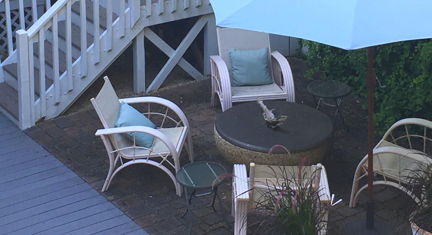 Chairs and a table in an outdoor seating group at the bottom of a set of stairs. 