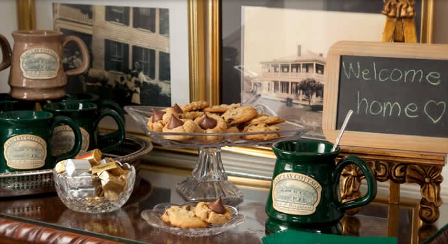 Cookies and treats on a sideboard with hand-thrown clay mugs and a sign that says "Welcome Home"