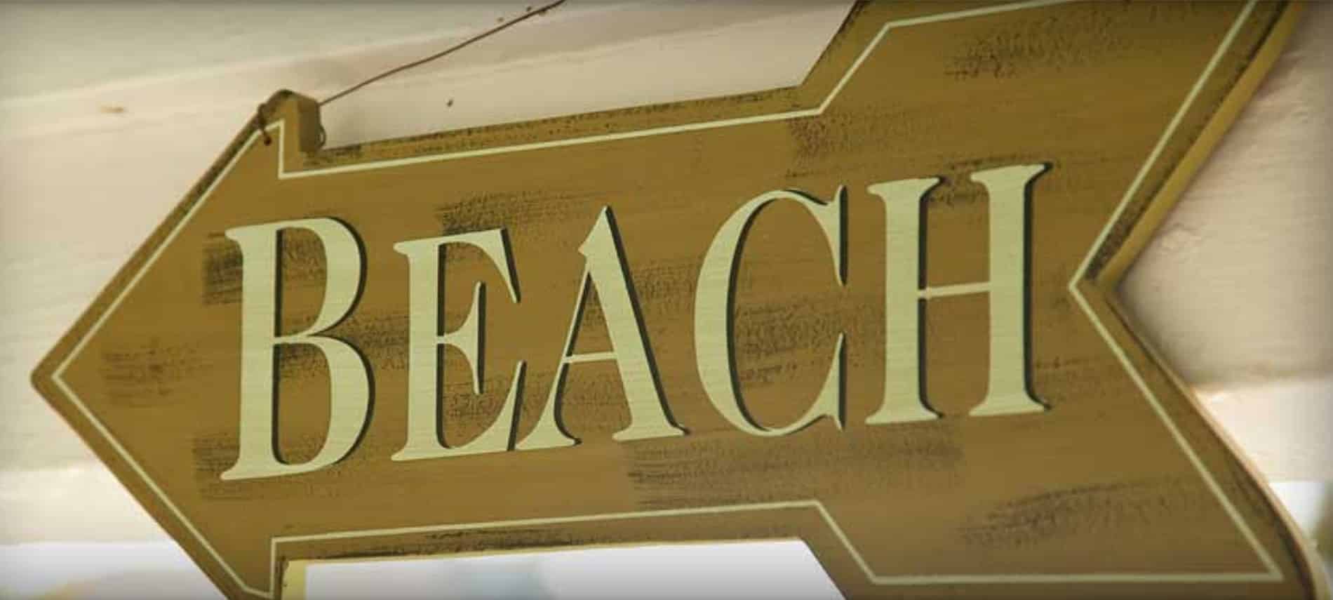 Large wooden arrow sign with the word "BEACH" in beige capital letters.