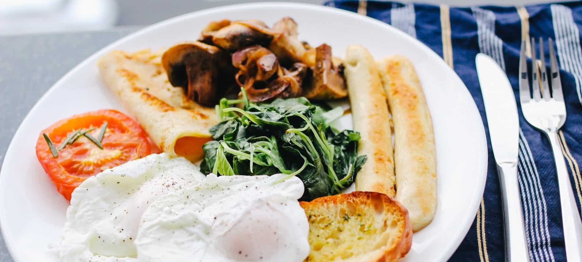 Poached eggs over toast with spinach, chicken sausage and a vegetable dish.