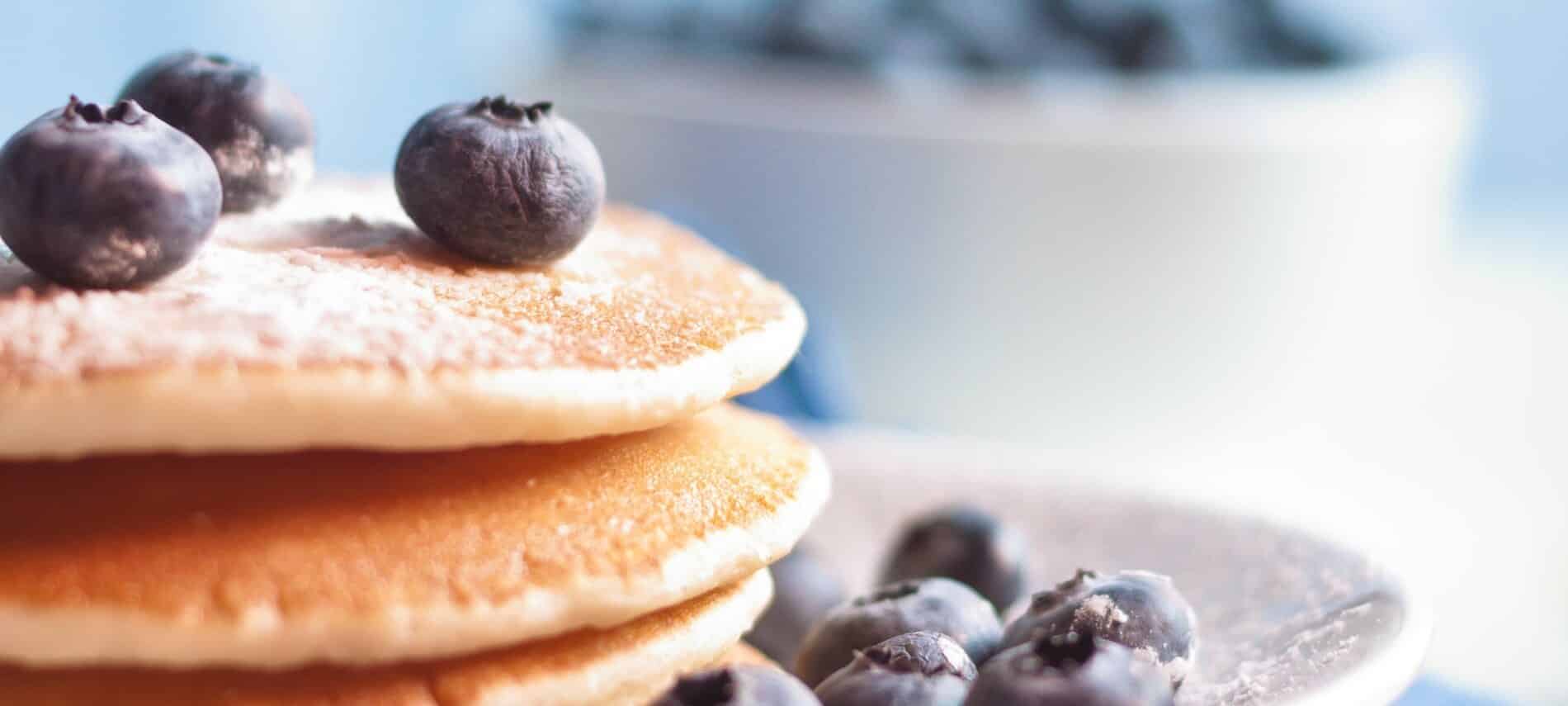 Stack of pancakes topped with blueberries and powdered sugar. 