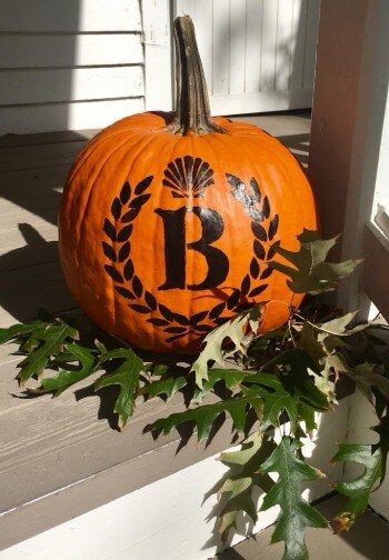 An orange pumkin with the Barclay Cottage Bed & Breakfast logo stenciled on it sits on a porch.